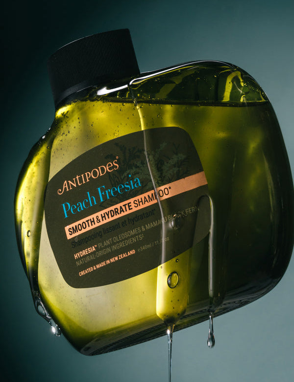 Antipodes Peach Freesia Smooth and Hydrate Shampoo bottle with product pour