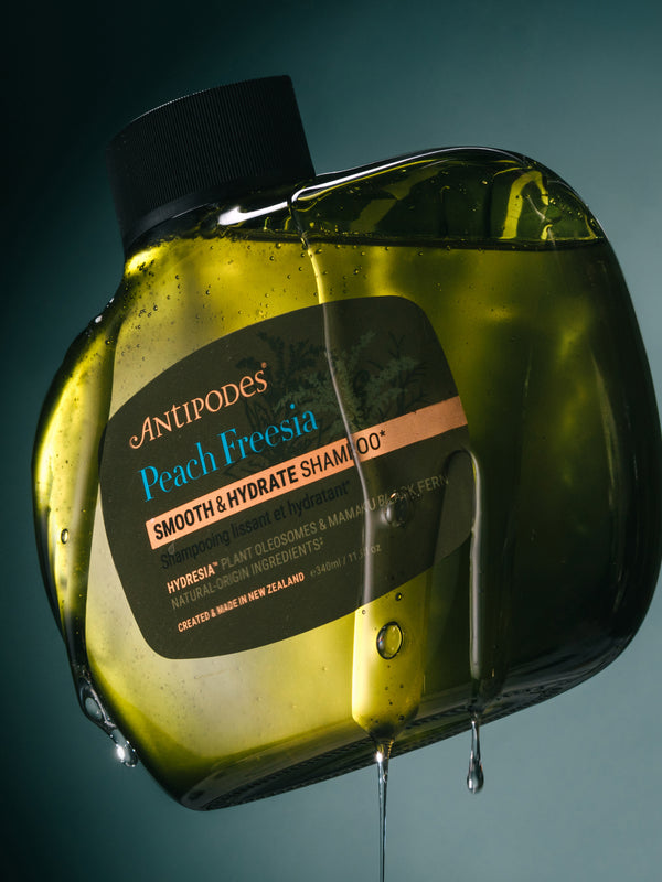 Antipodes Peach Freesia Smooth and Hydrate Shampoo bottle with product pour