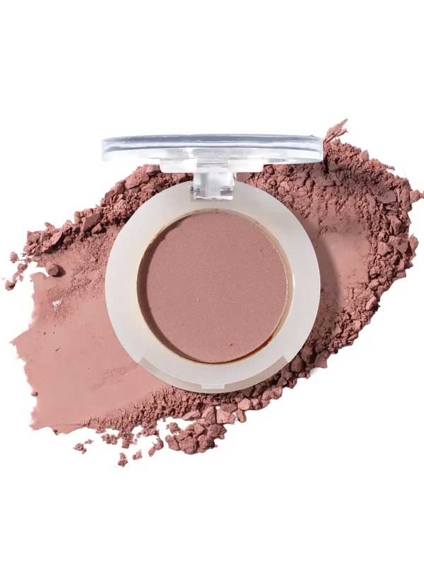 An open compact of 100% Pure Fruit Pigmented® Eye Shadow 2g by 100% Pure reveals matte mauve powder, some scattered nearby, resembling pressed powder blush against a clean white background.