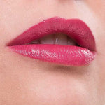 Close-up of lips wearing Benecos Natural Lipsticks 4.5g in a glossy pink rose shade, upper teeth slightly visible as the lower lip is gently bitten. The background and caption both match the Pink Rose color of the lipstick.