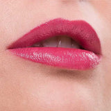 Close-up of lips wearing Benecos Natural Lipsticks 4.5g in a glossy pink rose shade, upper teeth slightly visible as the lower lip is gently bitten. The background and caption both match the Pink Rose color of the lipstick.