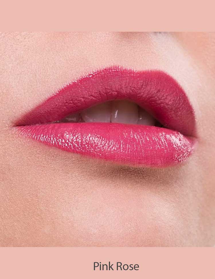 Close-up of lips wearing Benecos Natural Lipsticks 4.5g in a glossy pink rose shade, upper teeth slightly visible as the lower lip is gently bitten. The background and caption both match the Pink Rose color of the lipstick.