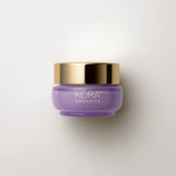 Small low purple 15 ml jar of KORA Plant Stem Cell Retinol Alternative Moisturiser with a wide gold lid, lying on a warm grey surface.