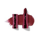 Black Rose lipstick in deep burgundy, standing in a reflective pink tube beside its botanical patterned cap, with a matching glossy colour smear behind.