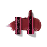 Black Rose lipstick in deep burgundy, standing in a reflective pink tube beside its botanical patterned cap, with a matching glossy colour smear behind.