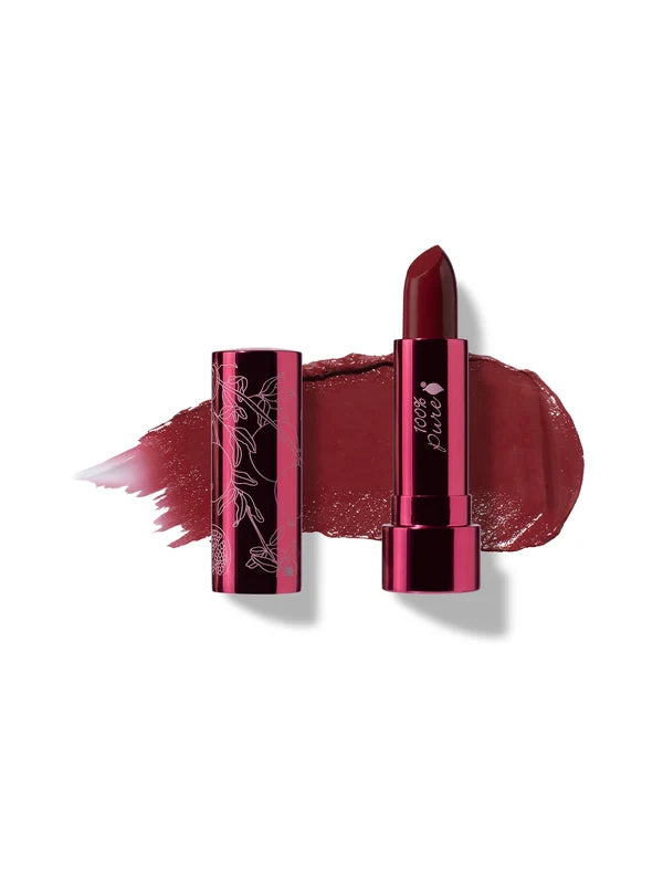 Black Rose lipstick in deep burgundy, standing in a reflective pink tube beside its botanical patterned cap, with a matching glossy colour smear behind.