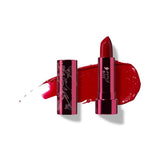 Poppy lipstick in rich red, standing in a reflective pink tube beside its botanical patterned cap, with a matching glossy red smear behind.