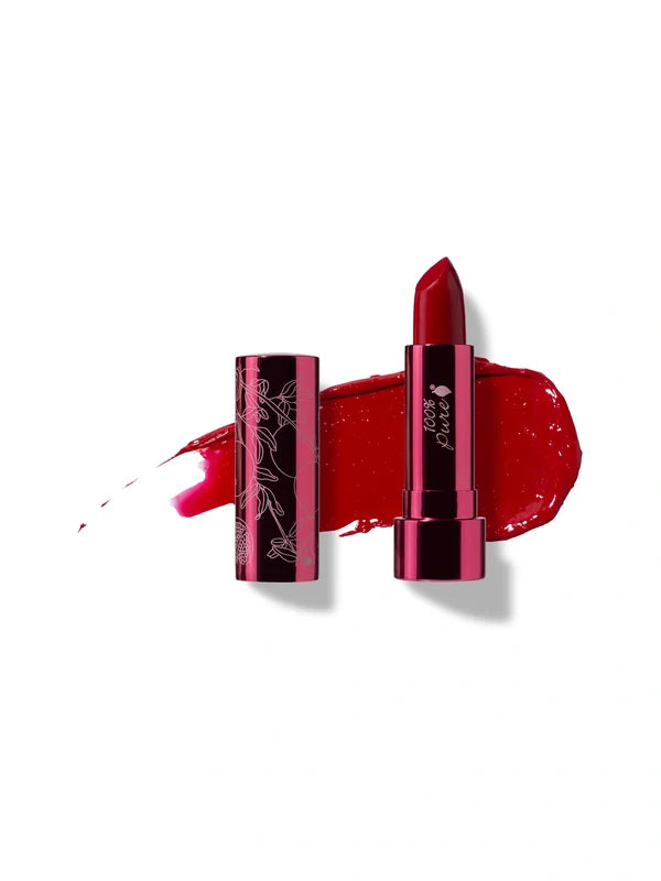 Poppy lipstick in rich red, standing in a reflective pink tube beside its botanical patterned cap, with a matching glossy red smear behind.