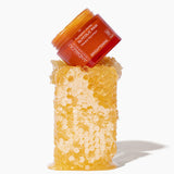 Andalou Naturals Brightening Pumpkin Honey Glycolic Mask jar resting on fresh honeycomb