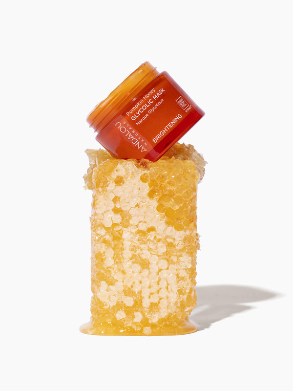 Andalou Naturals Brightening Pumpkin Honey Glycolic Mask jar resting on fresh honeycomb
