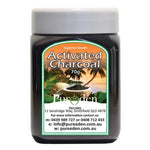 A jar labeled Pure Eden Activated Charcoal 150g sits before a tropical backdrop of palm trees and a waterfall. Made in Australia from coconut shell charcoal, the label includes contact details and an address.