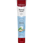 Upright white Red Seal Baking Soda Hydroxyapatite toothpaste tube with a red cap, a pale blue lower panel and mint leaves beside a wooden spoon of white powder.