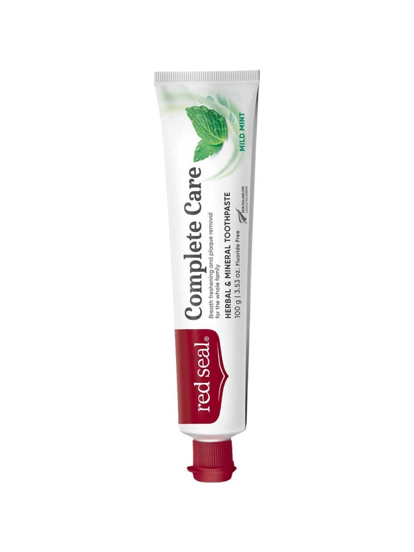 Slender white Red Seal Complete Care toothpaste tube standing on a small red cap, with large black lettering, a red logo panel and green mint leaves near the top.
