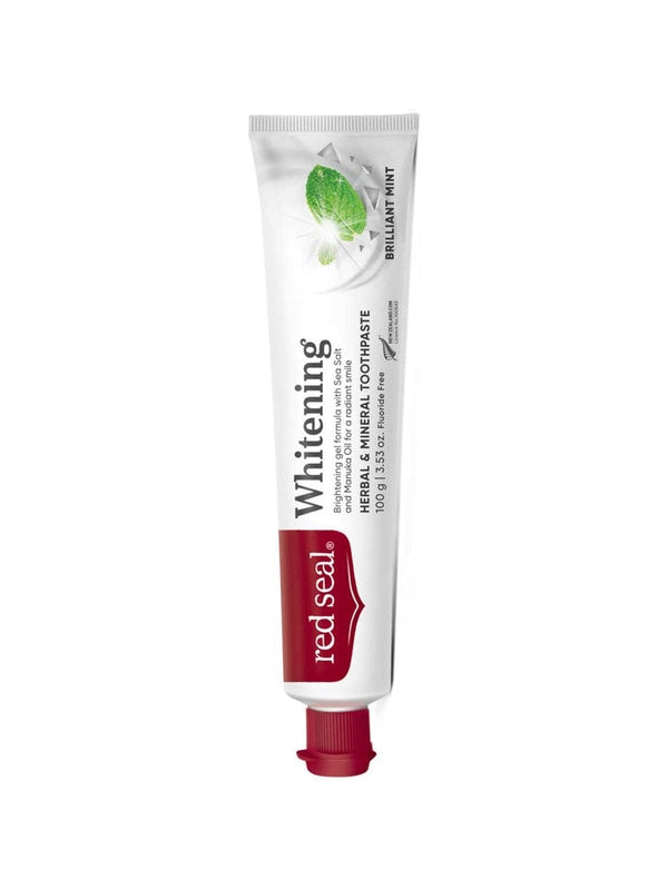 Slender white Red Seal Whitening toothpaste tube standing on a small red cap, with a red logo panel, black lettering and pale green mint leaves near the top.