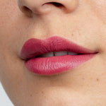 Close-up of lips wearing Antipodes Moisture Boost Natural Lipsticks 4g in matte red, showing smooth, even coverage. Lower nose and cheek are visible. Text at the bottom reads Remarkably Red.
