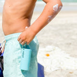 Wotnot refillable sunscreen roll-on applicator used with a child at the beach