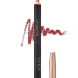 A rose-colored INIKA Organic Lip Crayon 6.7g with a swatch of the long-lasting lip liner shade scribbled behind it; the cap sits beside the crayon. Text below shows "Rose Petal.