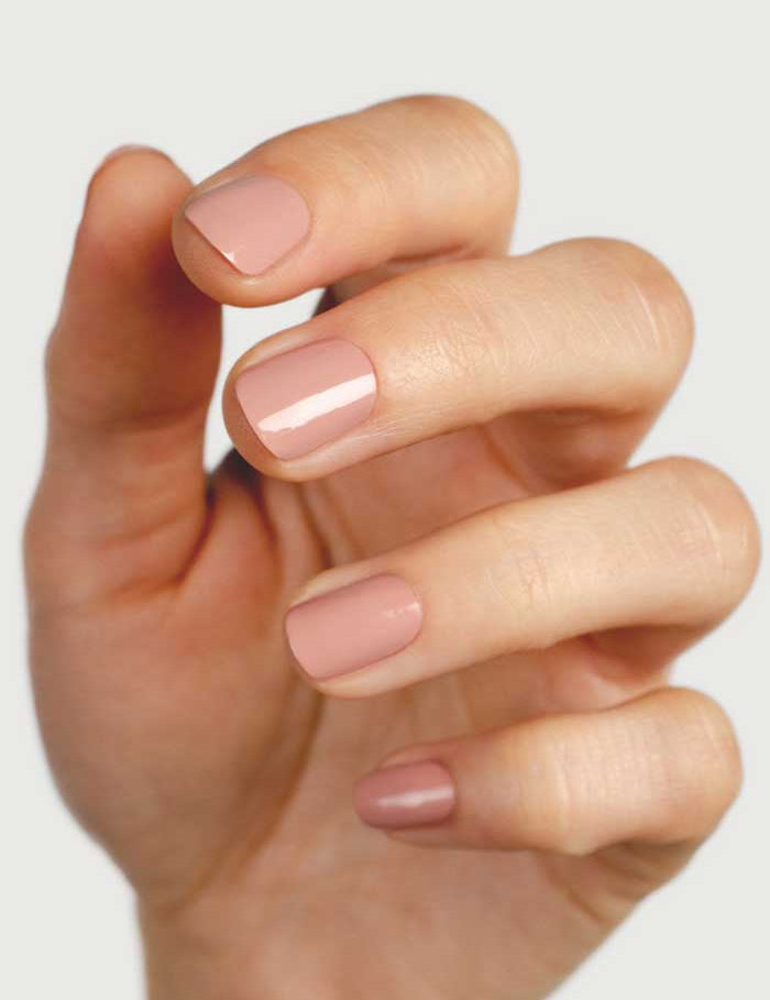 A hand with short, neatly shaped nails painted in Sienna Byron Bay Nail Polish - Rosie, a glossy dusty rose nude shade, is shown against a plain light background. The fingers are slightly curled to display the polished nails.