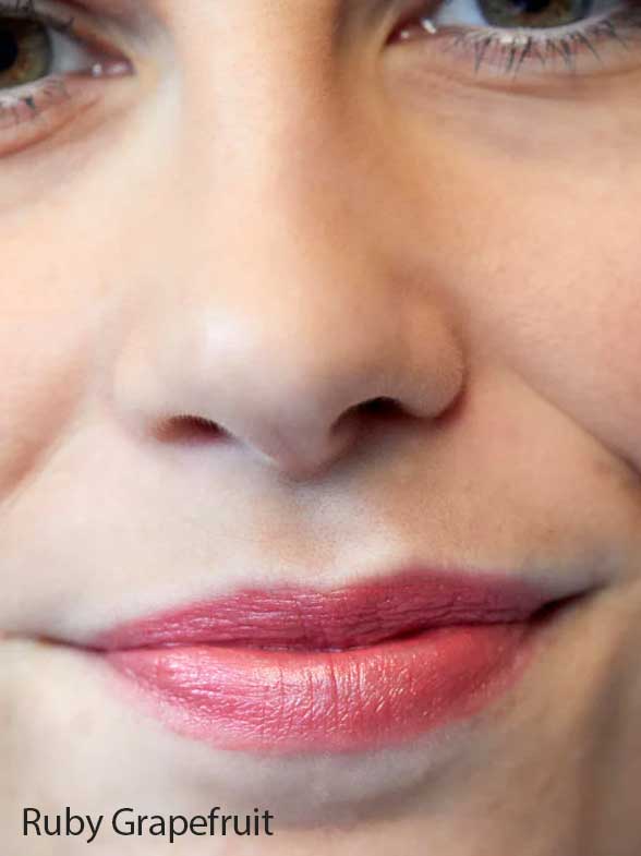 A close-up of the lower half of a person’s face with natural makeup and pinkish-red Luk Beautifood Lip Nourish Lipsticks 3g, enriched with nourishing Avocado Oil. The words Ruby Grapefruit appear in the bottom left corner.