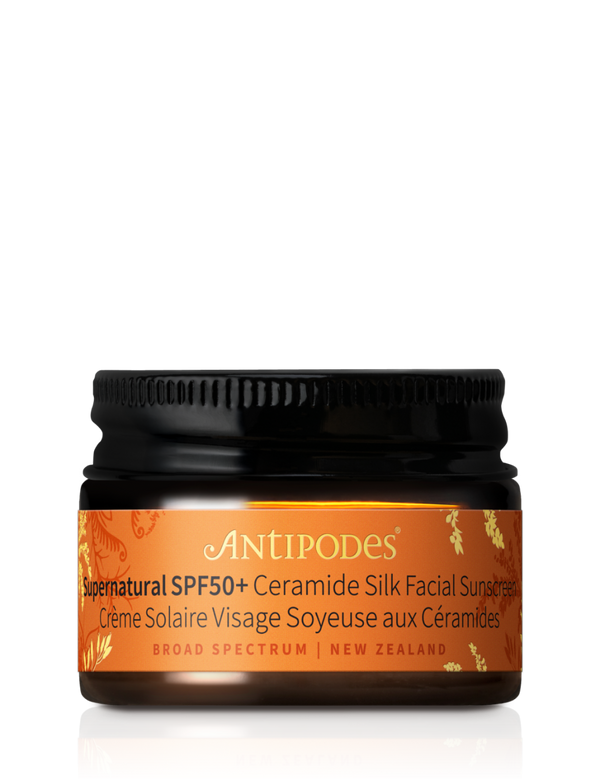 Miniature Antipodes Supernatural SPF50+ Facial Sunscreen in a small amber glass jar with an orange and gold label and a ribbed black screw lid.