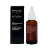 Back of an amber Noosa Basics Scalp Serum bottle beside its black carton, showing white application directions and care instructions.