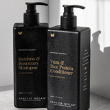 Black rectangular Vanessa Megan Yuzu & Rice Protein Conditioner and Bamboo & Rosemary Shampoo pump bottles stand together in sunlight, with water droplets on their surfaces.