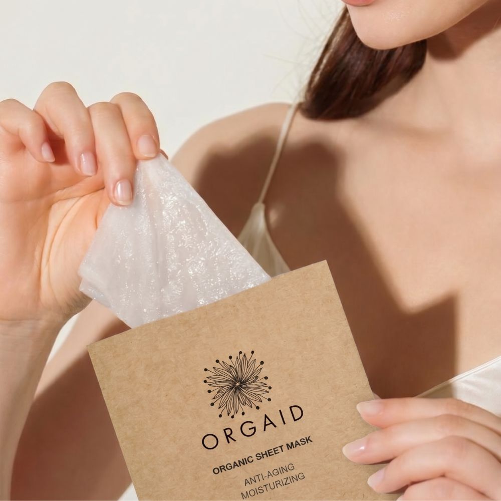 Woman removing an Orgaid Anti-Aging and Moisturising Organic Sheet Mask from its packet