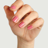 A close-up of a hand with neatly manicured nails painted in Sienna Byron Bay's Blossom, a glossy pink polish, set against a plain light gray background.