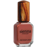 Clear rectangular Sienna Byron Bay Life nail-polish bottle filled with muted terracotta-red polish, with black lettering and a tall wood-grain cap.