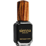A bottle of Sienna Byron Bay Nail Polish in Onyx, featuring a wooden cap, is shown against a white background.