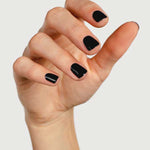 A hand with short, neatly manicured nails painted in Sienna Byron Bay's Onyx polish, set against a plain light background.