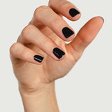 A hand with short, neatly manicured nails painted in Sienna Byron Bay's Onyx polish, set against a plain light background.