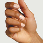A close-up of a hand with medium-brown skin and neatly manicured nails painted in Sienna Byron Bay Nail Polish - Posy, held against a plain light background.