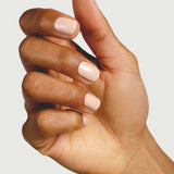 A close-up of a hand with medium-brown skin and neatly manicured nails painted in Sienna Byron Bay Nail Polish - Posy, held against a plain light background.