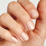 A close-up of a hand with neatly manicured nails painted in Sienna Byron Bay Nail Polish - Posy, a glossy pale nude shade, against a light background.