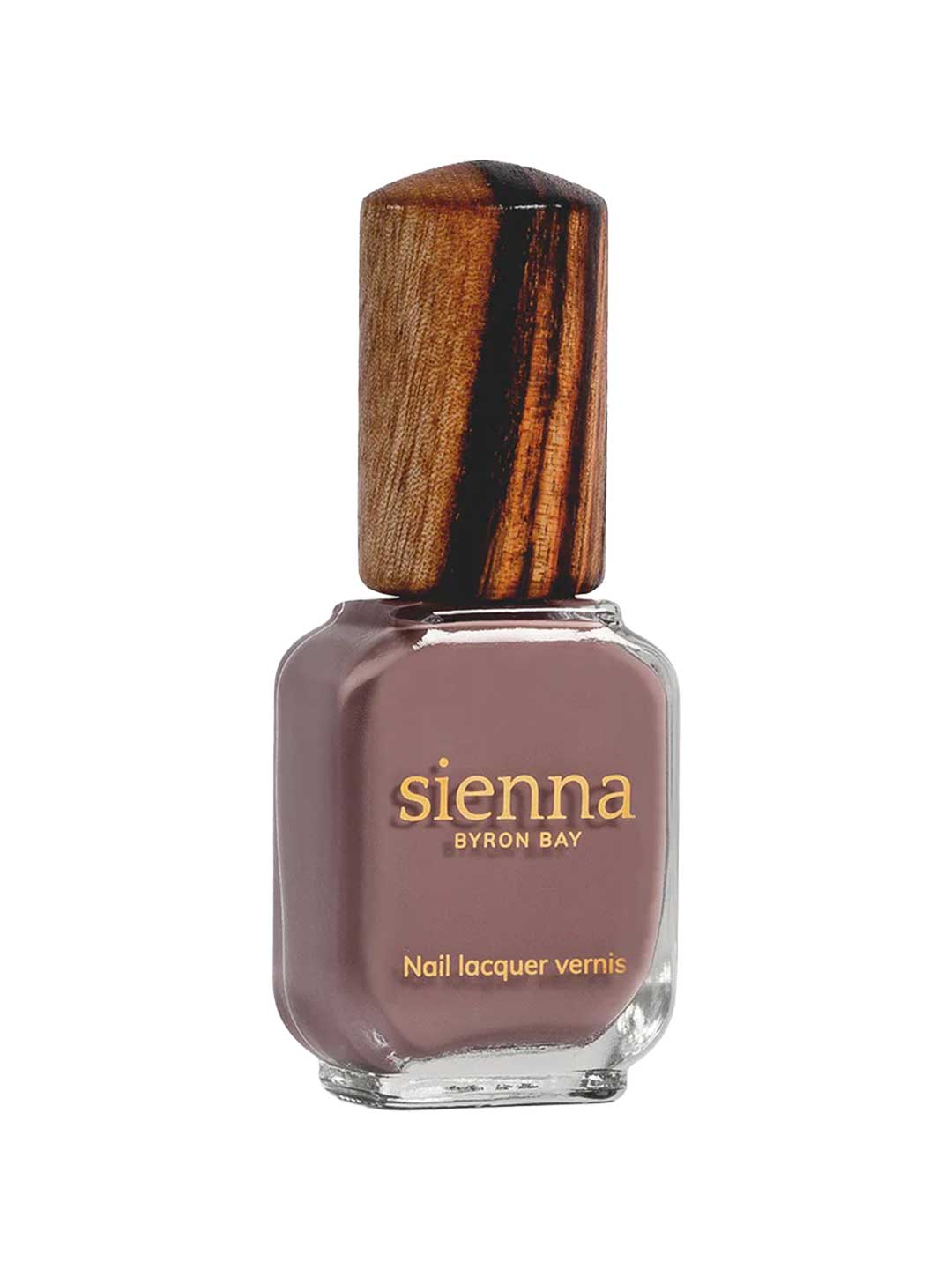A rectangular glass bottle of Sienna Byron Bay Nurture nail polish, featuring a brownish-mauve shade, gold label with brand and product info, and a wooden cap.