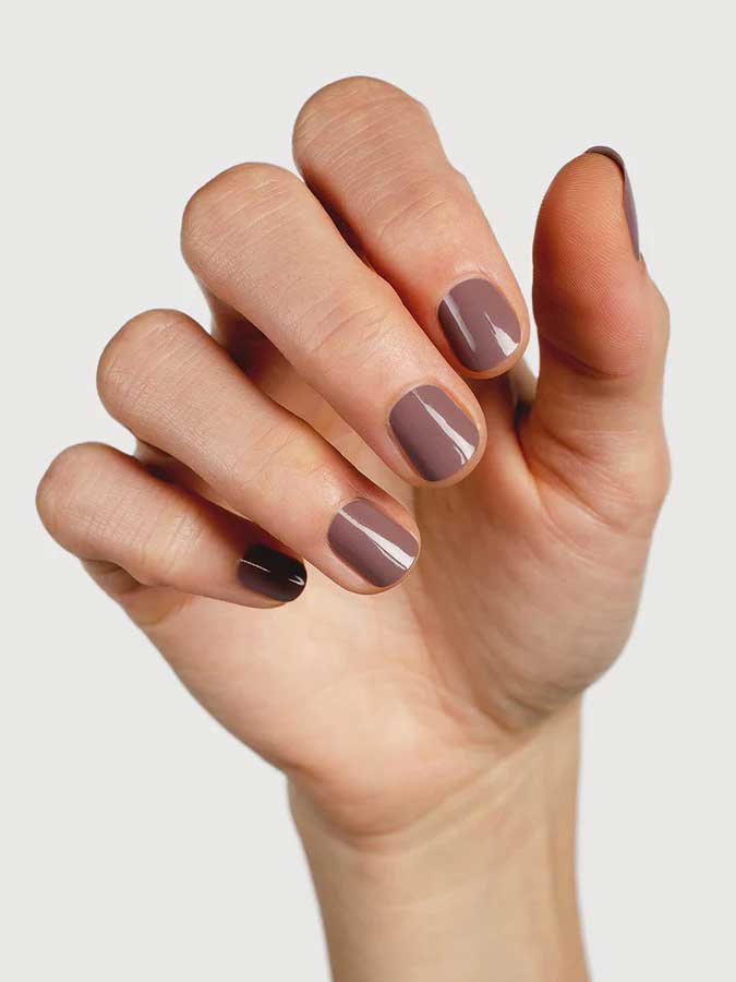 A hand with neatly manicured nails painted in Sienna Byron Bay Nurture, a glossy mauve-brown shade by Sienna Byron Bay, is held against a plain light background.
