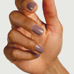 A close-up of a hand with medium brown skin and neatly manicured nails painted in Sienna Byron Bay Nurture, a glossy light mauve shade by Sienna Byron Bay, against a plain light background.