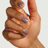 A close-up of a hand with medium brown skin and neatly manicured nails painted in Sienna Byron Bay Nurture, a glossy light mauve shade by Sienna Byron Bay, against a plain light background.