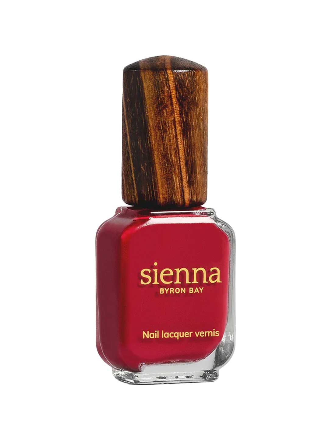 A bottle of Sienna Byron Bay Heart red nail lacquer by Sienna Byron Bay, featuring a wooden cap and gold lettering on the front.