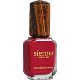 A bottle of Sienna Byron Bay Heart red nail lacquer by Sienna Byron Bay, featuring a wooden cap and gold lettering on the front.
