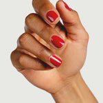 A hand with medium brown skin displays neatly manicured nails painted in Sienna Byron Bay’s Heart, a glossy red shade, against a plain white background.