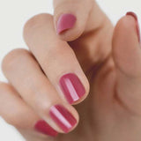 A close-up of a hand with short nails painted in Sienna Byron Bay Heartspace pink polish by Sienna Byron Bay, set against a plain, light background.