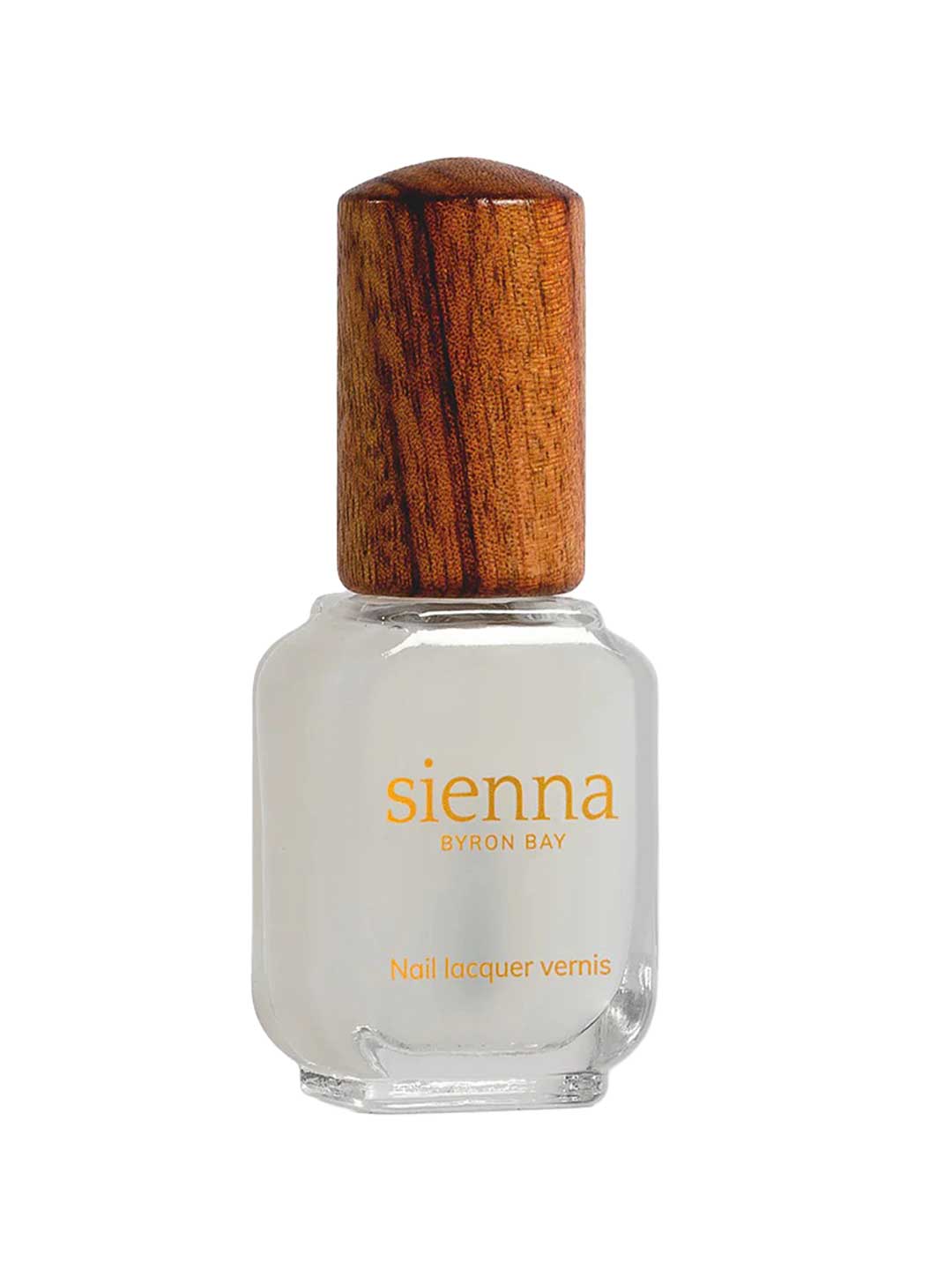 A clear glass bottle of Sienna Byron Bay Matte Top Coat with a wooden cap. The yellow label reads sienna BYRON BAY and Matte Top Coat. The bottle holds a white or pale matte top coat nail polish.