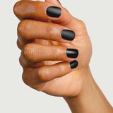 A hand with short, neatly manicured nails painted in matte black, finished with Sienna Byron Bay Matte Top Coat by Sienna Byron Bay, is shown against a plain light background.