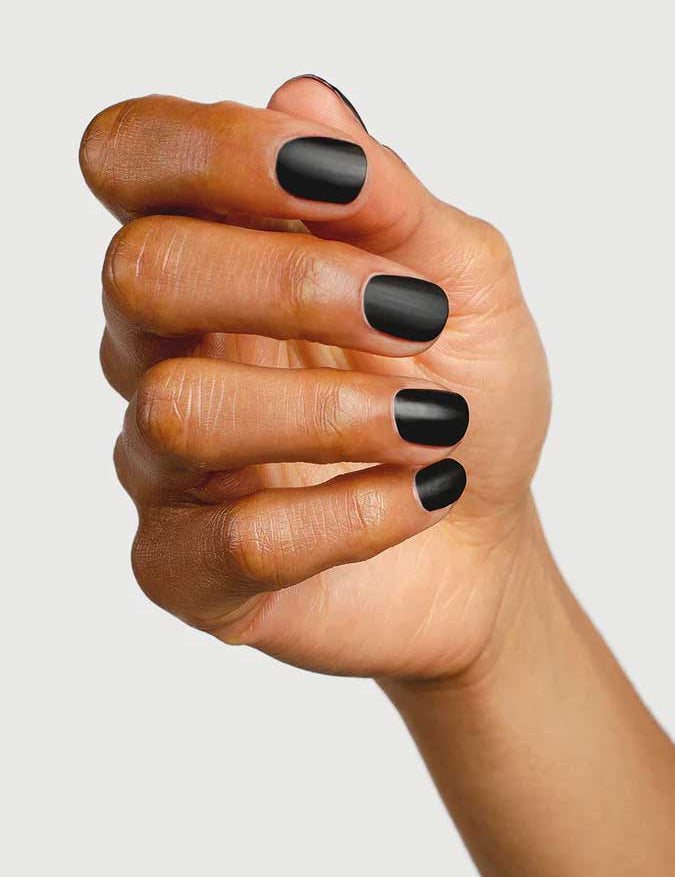 A hand with short, neatly manicured nails painted in matte black, finished with Sienna Byron Bay Matte Top Coat by Sienna Byron Bay, is shown against a plain light background.