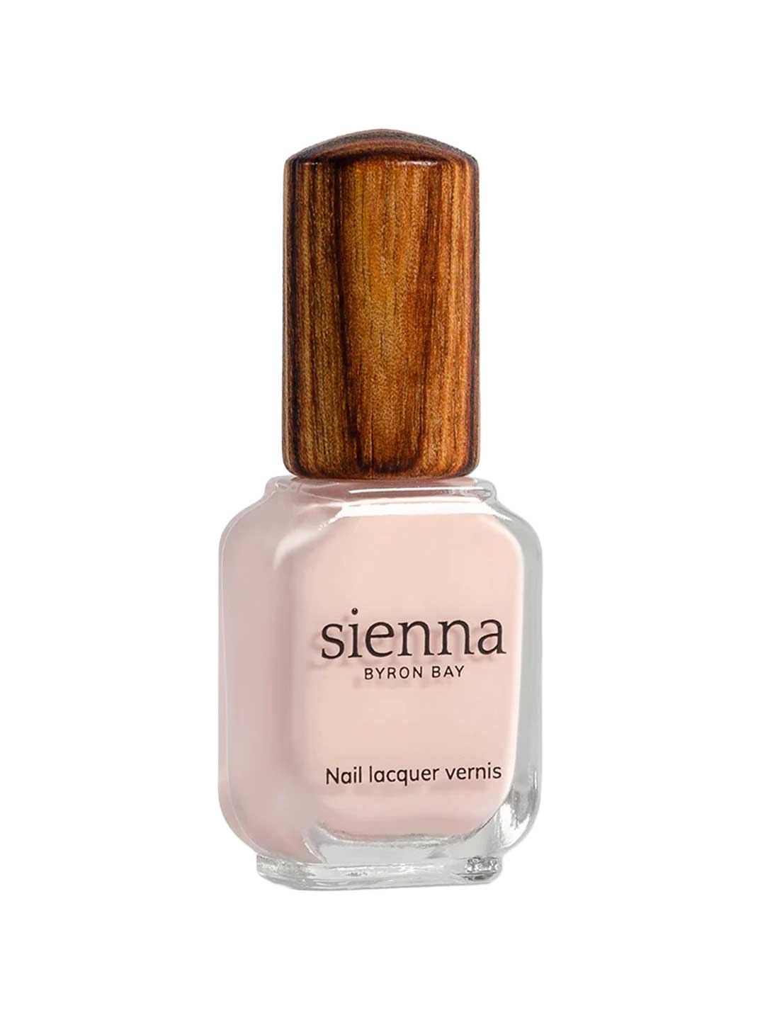 A bottle of Sienna Byron Bay Melody nail lacquer with light pink polish and a wooden-textured cap is shown against a white background.