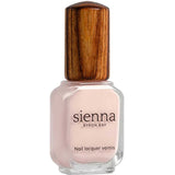 A bottle of Sienna Byron Bay Melody nail lacquer with light pink polish and a wooden-textured cap is shown against a white background.
