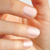 A close-up of a hand with neatly manicured, short nails painted in Sienna Byron Bay Melody, a pale pink shade by Sienna Byron Bay. The fingers are slightly bent and the nails are evenly shaped.