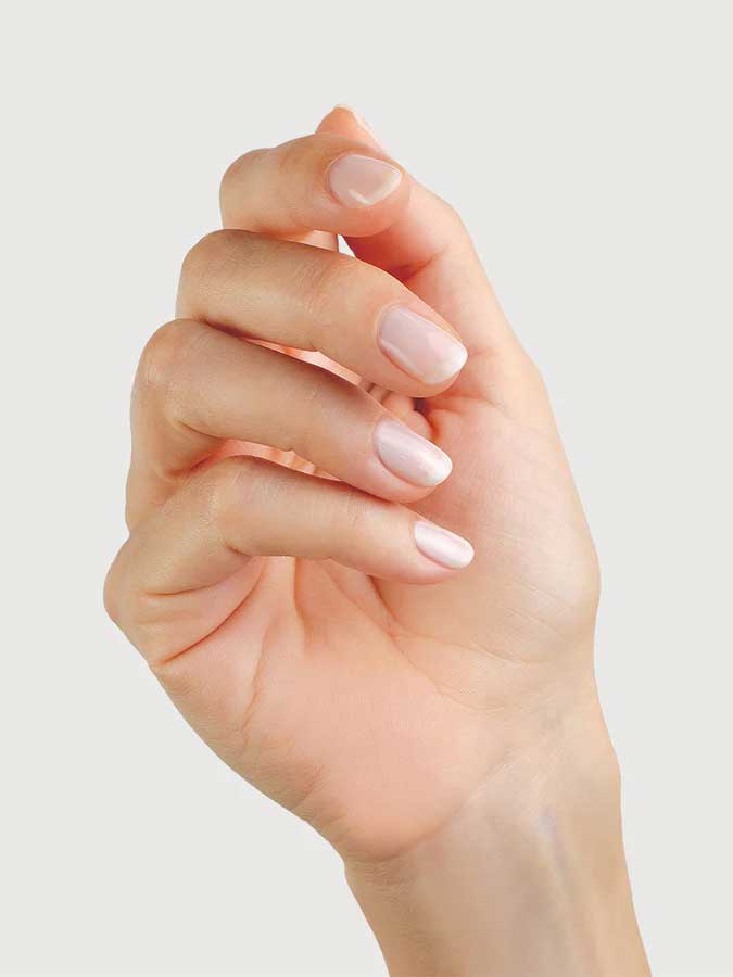 A close-up of a hand with neatly manicured nails painted in Sienna Byron Bay - Hope by Sienna Byron Bay, slightly curled inward against a light, plain background.